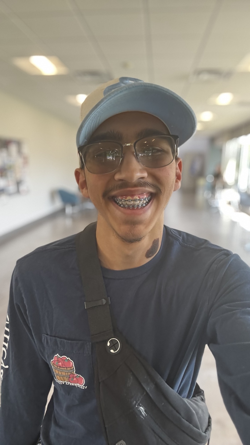 Josiah Feliciano smiling in a cap and glasses